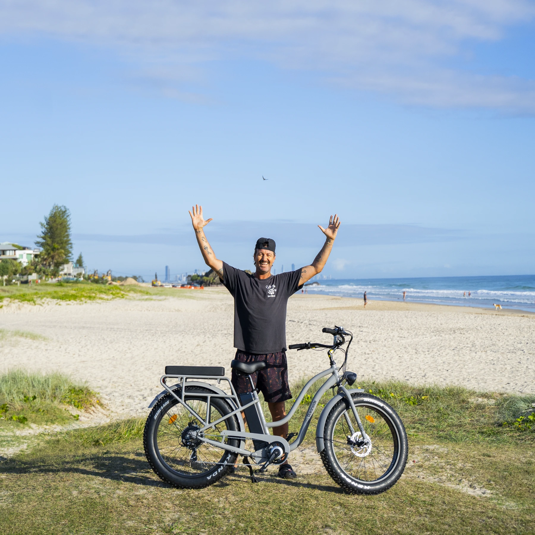 Happy rider with an Oceanside Hire e-bike on the beach at Burleigh Heads